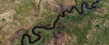 Pohled z dronu na bezlesí s kroutícím se korytem Padrťského potoka.